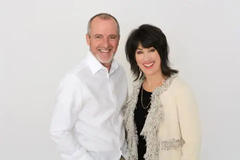 Two smiling individuals stand side by side against a plain white background.